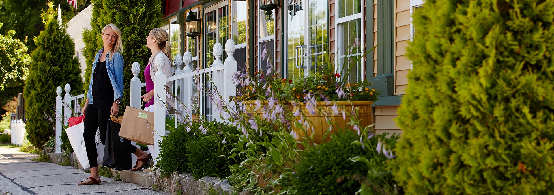 Two women coming out of a shop with bags in their hands.