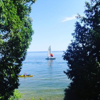 A sailboat and kayak on the lake between the trees.