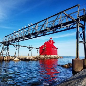 A red lighthouse at the end of a pier.